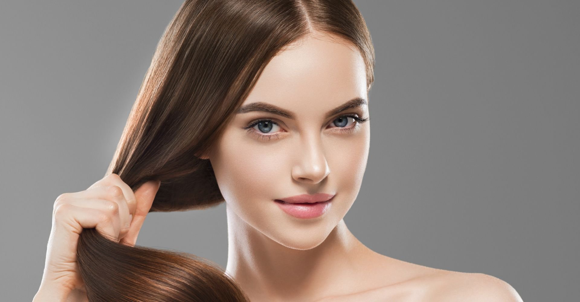 Menina olhando para a câmera enquanto segura seu cabelo castanho médio.