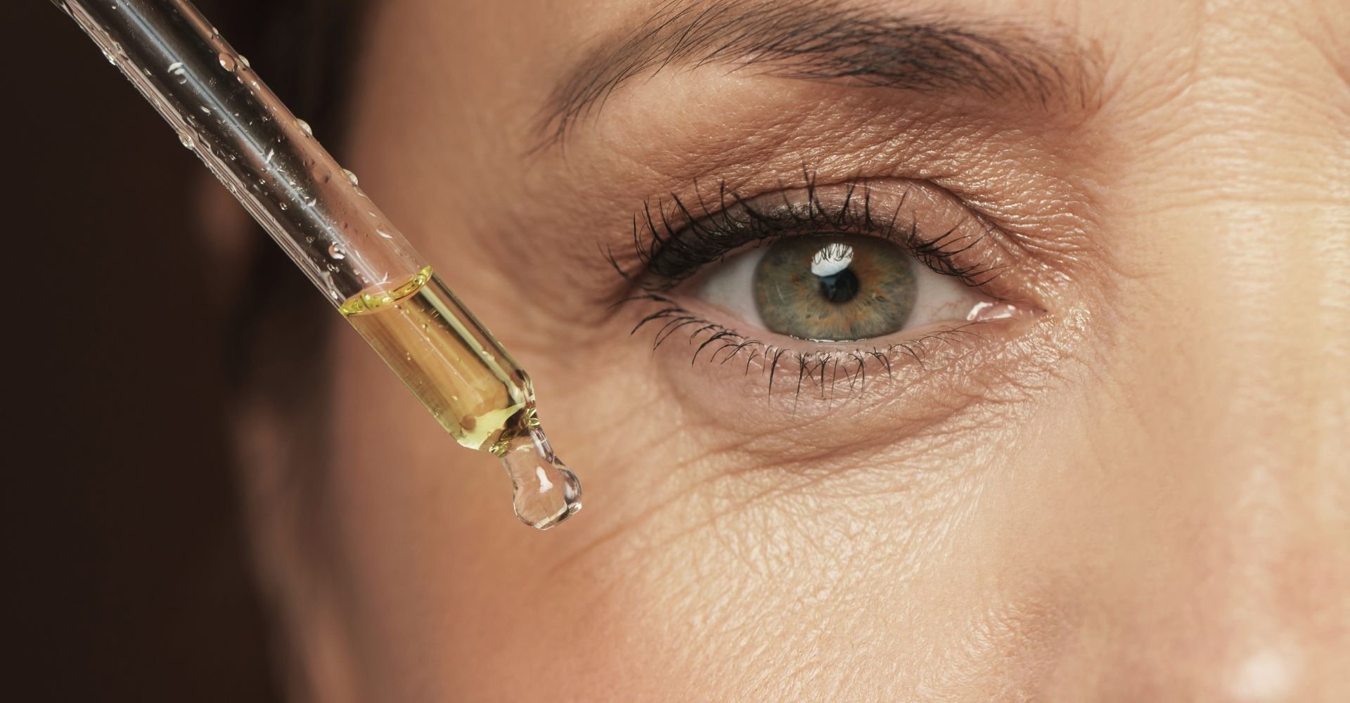 Mulher madura aplicando um sérum com ácido para o rosto em sua pele facial