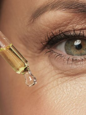 Mulher madura aplicando um sérum com ácido para o rosto em sua pele facial