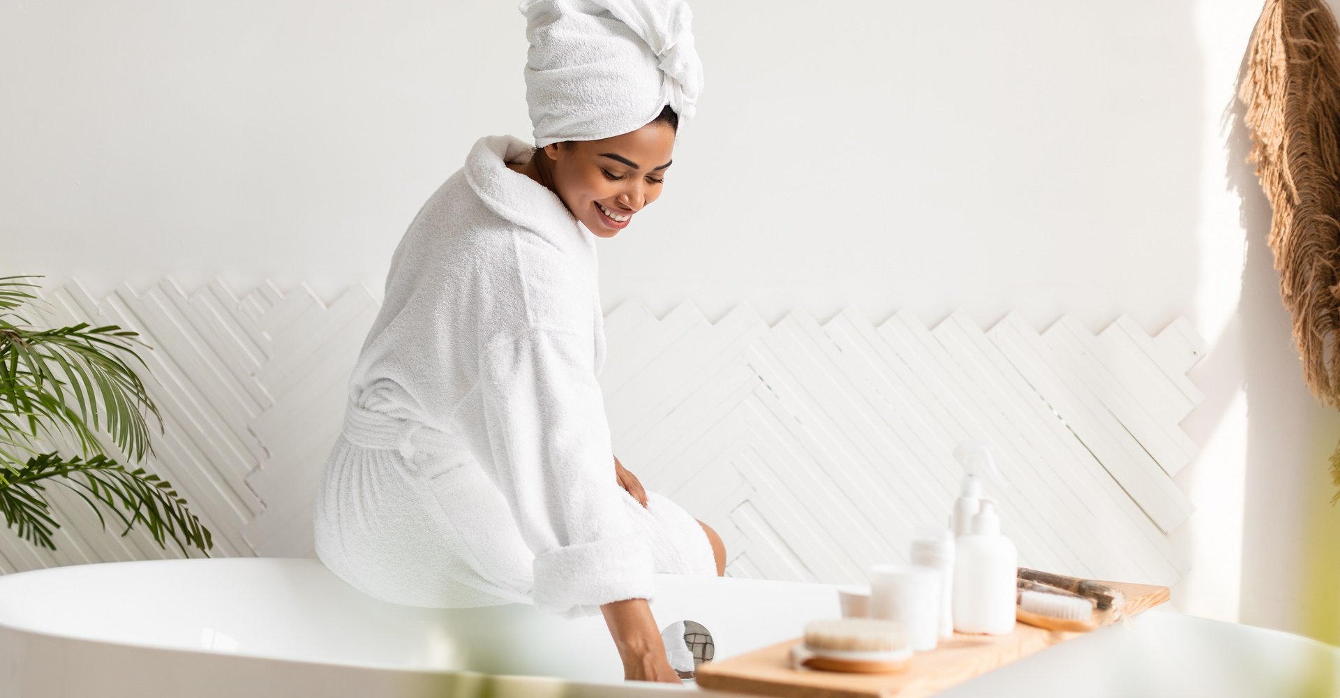 Mulher fazendo um banho premium na banheira com vários produtos apoiados.