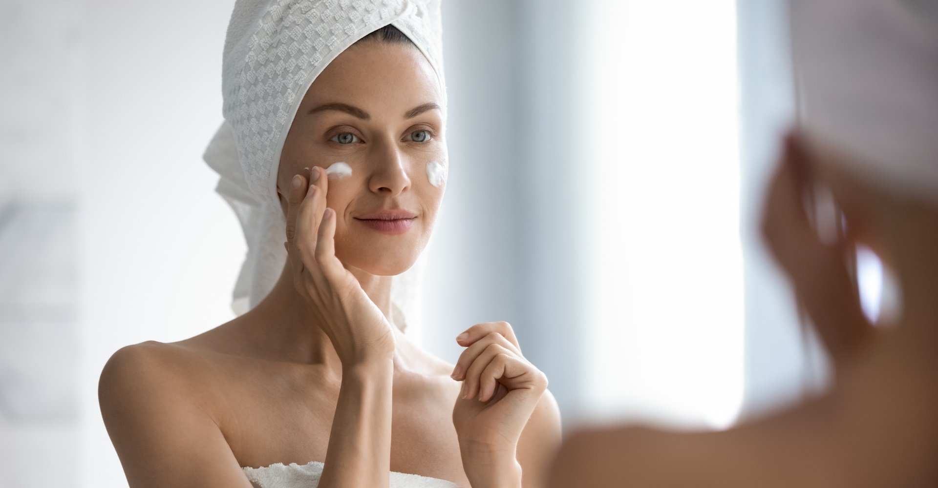 Mulher passando creme facial noturno no rosto.