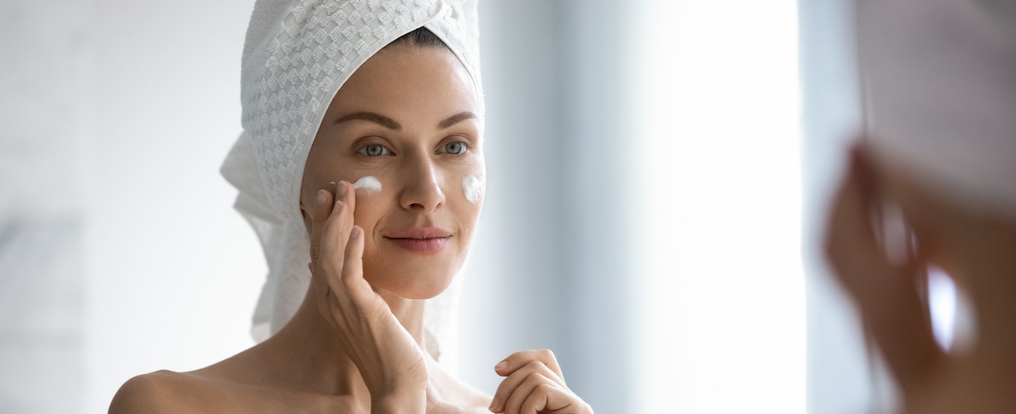 Mulher passando creme facial noturno no rosto.