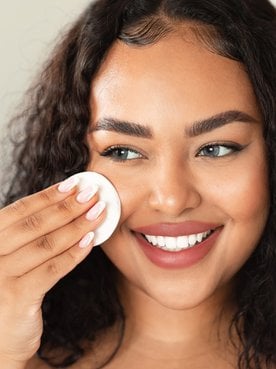 Mulher utiliza demaquilante bifásico para remover a maquiagem do rosto