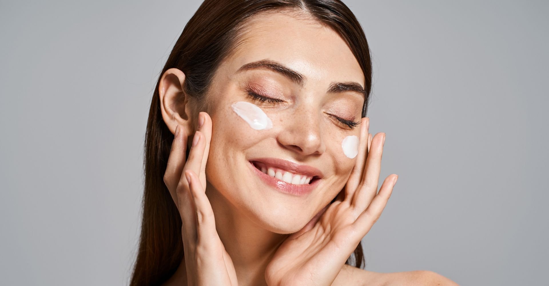 Mulher sorridente com protetor solar para o rosto nas bochechas.