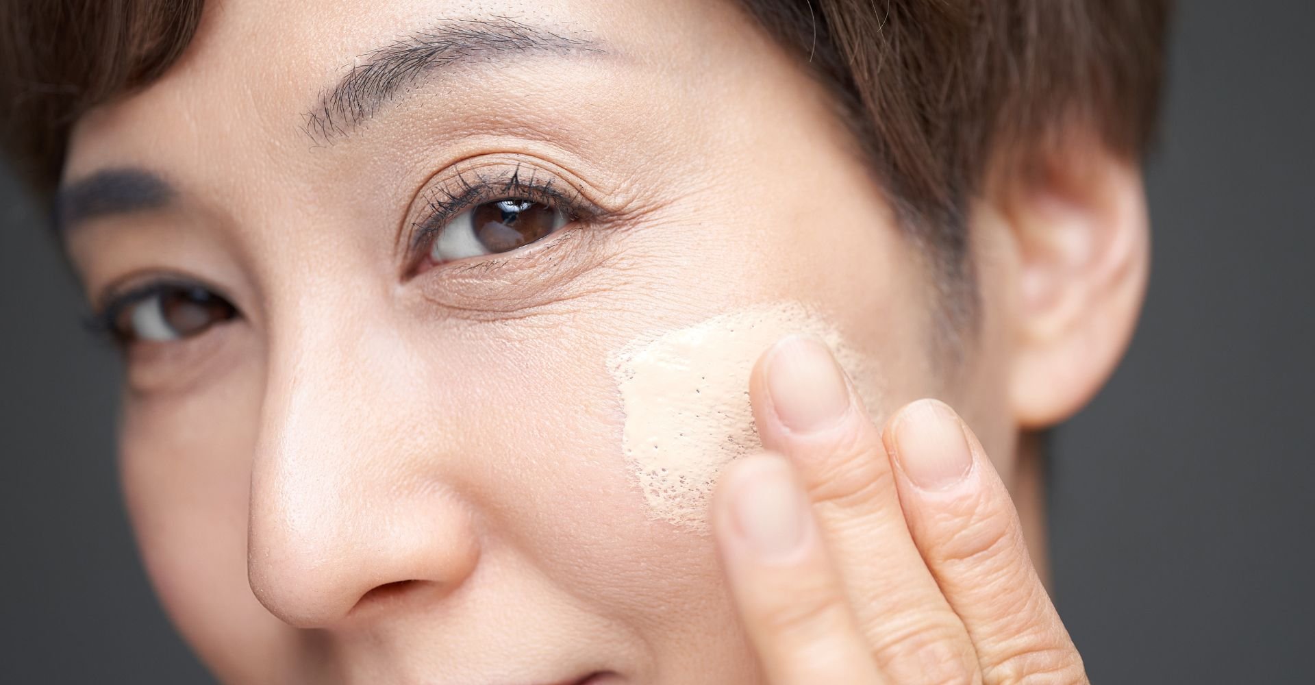 Mulher asiática passando protetor solar com cor no rosto