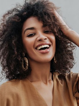 Mulher com tinta de cabelo castanho escuro em seu cabelo cacheado.