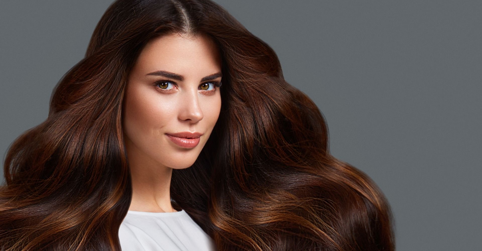 Mulher olhando para a câmera com cabelo longo e cheio na cor chocolate.