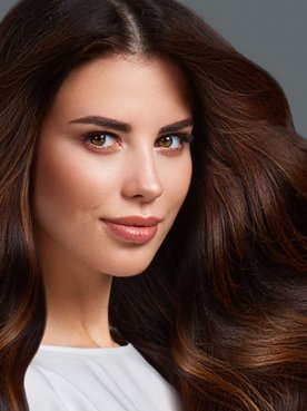 Mulher olhando para a câmera com cabelo longo e cheio na cor chocolate.