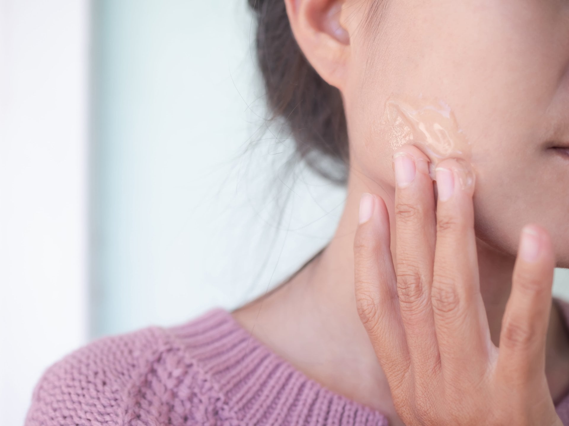 Mulher aplica gel hidratante com vitamina b5 ou pantenol para hidratar a pele facial.