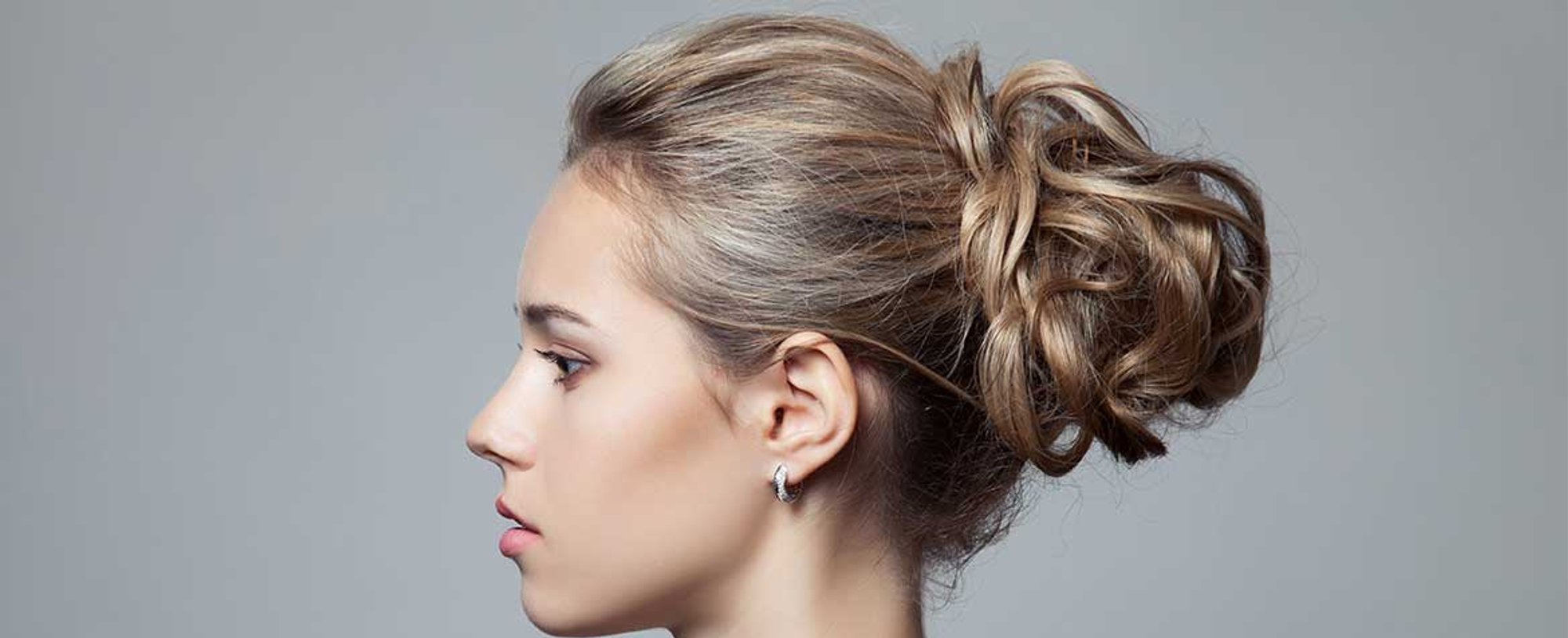 Modelo loira de lado com coque no cabelo