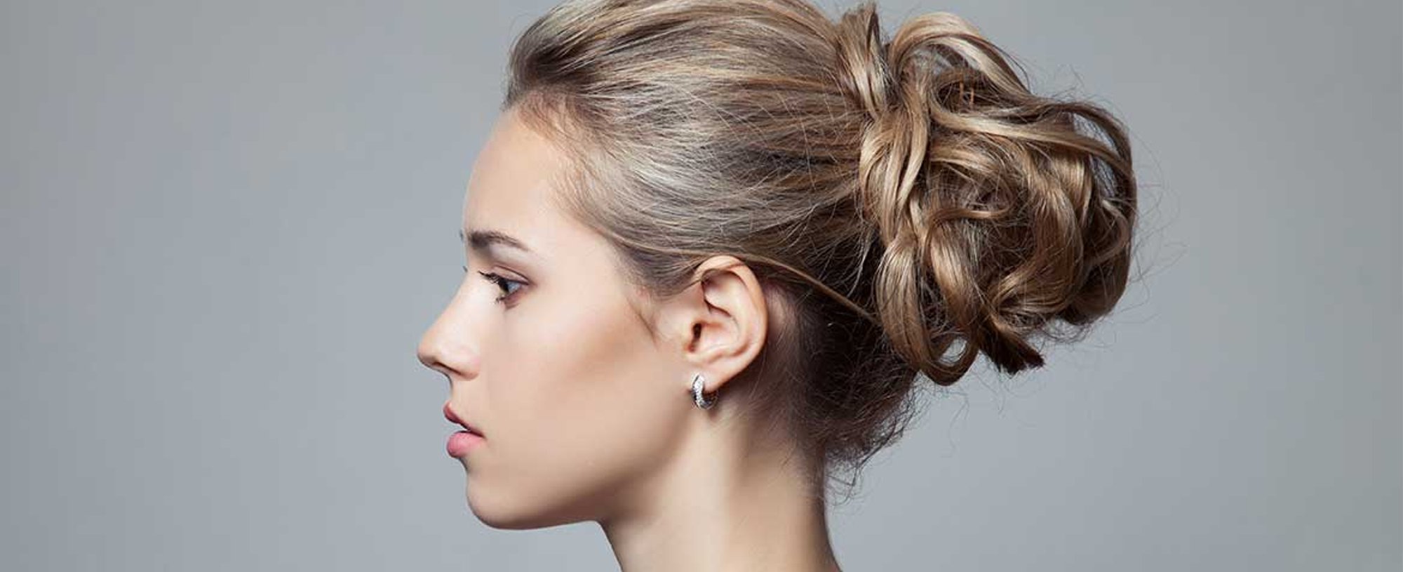 Modelo loira de lado com coque no cabelo