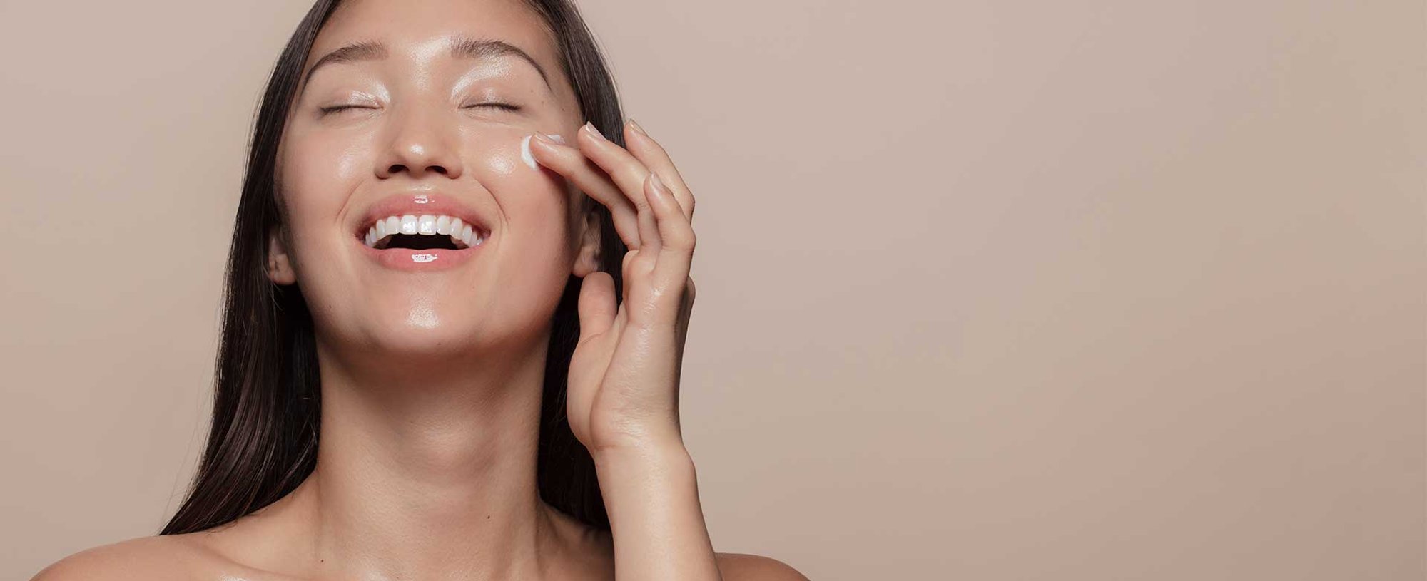 Modelo asiatica sorrindo passando produto em sua pele