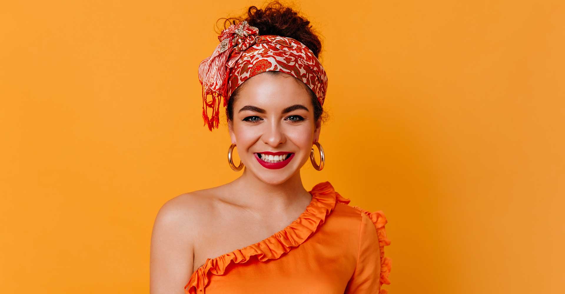 Modelo com cabelo preso e coque alto sorrindo