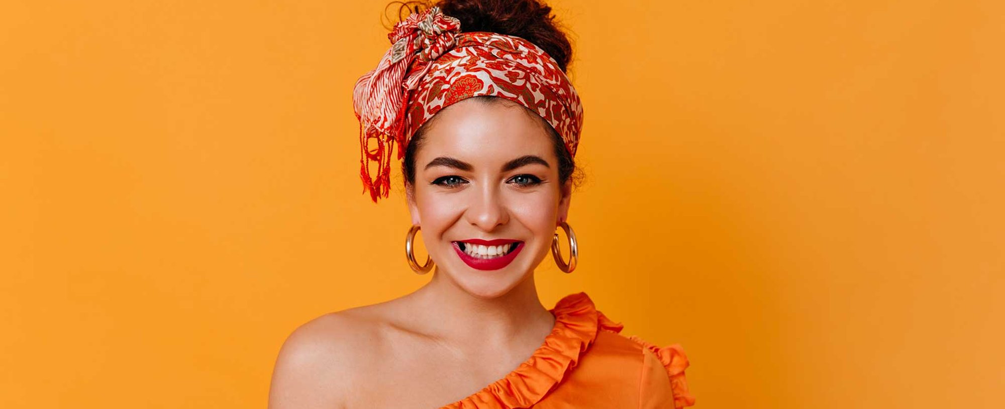 Modelo com cabelo preso e coque alto sorrindo