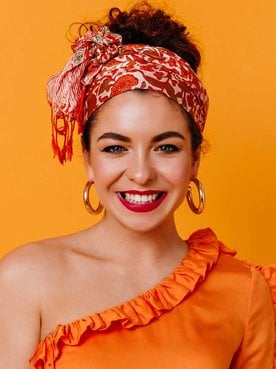 Modelo com cabelo preso e coque alto sorrindo