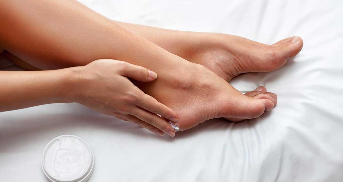 Mulher passando produto em seus pes