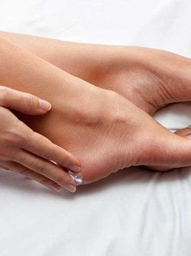 Mulher passando produto em seus pes