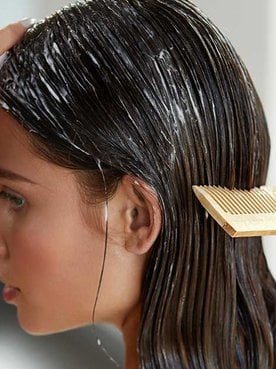 Modelo passando pente em seu cabelo com produto