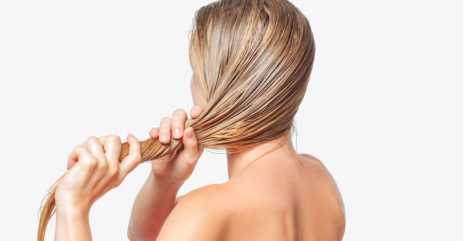 Modelo loira de costas arrumando seu cabelo