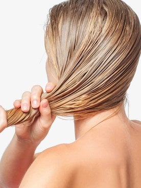 Modelo loira de costas arrumando seu cabelo