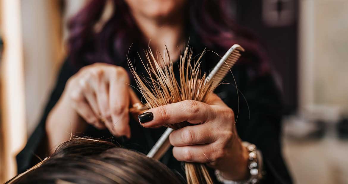 Profissional cortando cabeo loiro de uma mulher
