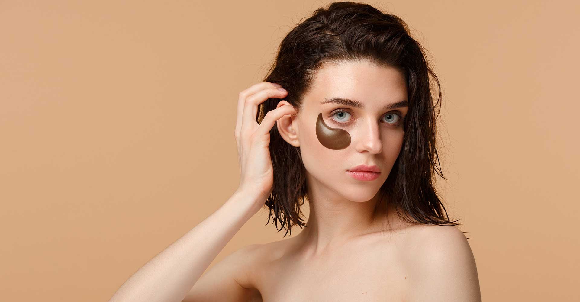 Modelo olhando para camera com um produto de tom escuro em seu rosto