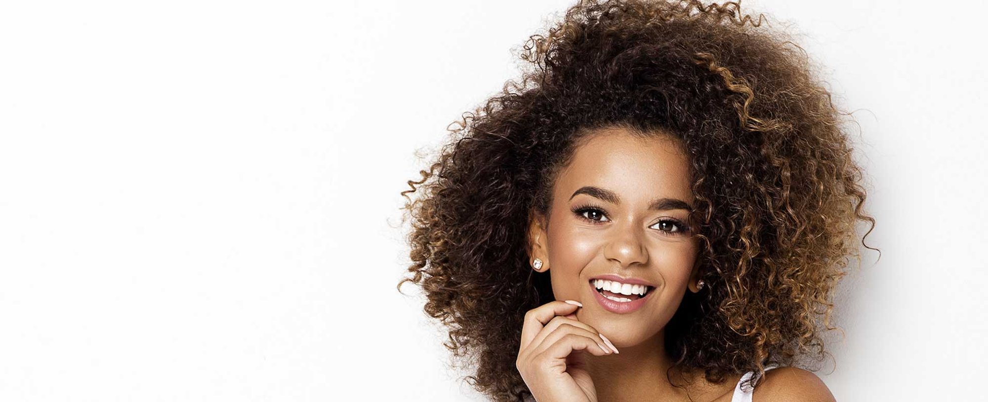 Modelo morena com cabelos castanhos cacheados volumoso