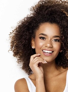 Modelo morena com cabelos castanhos cacheados volumoso