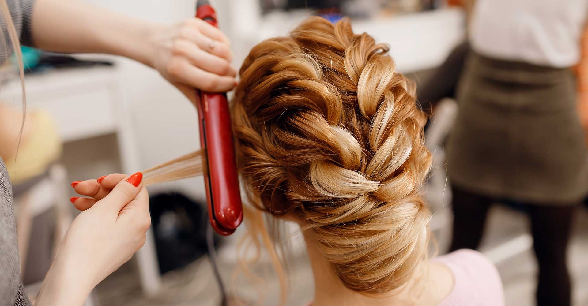 Profissional passando chapinha em um cabelo loiro