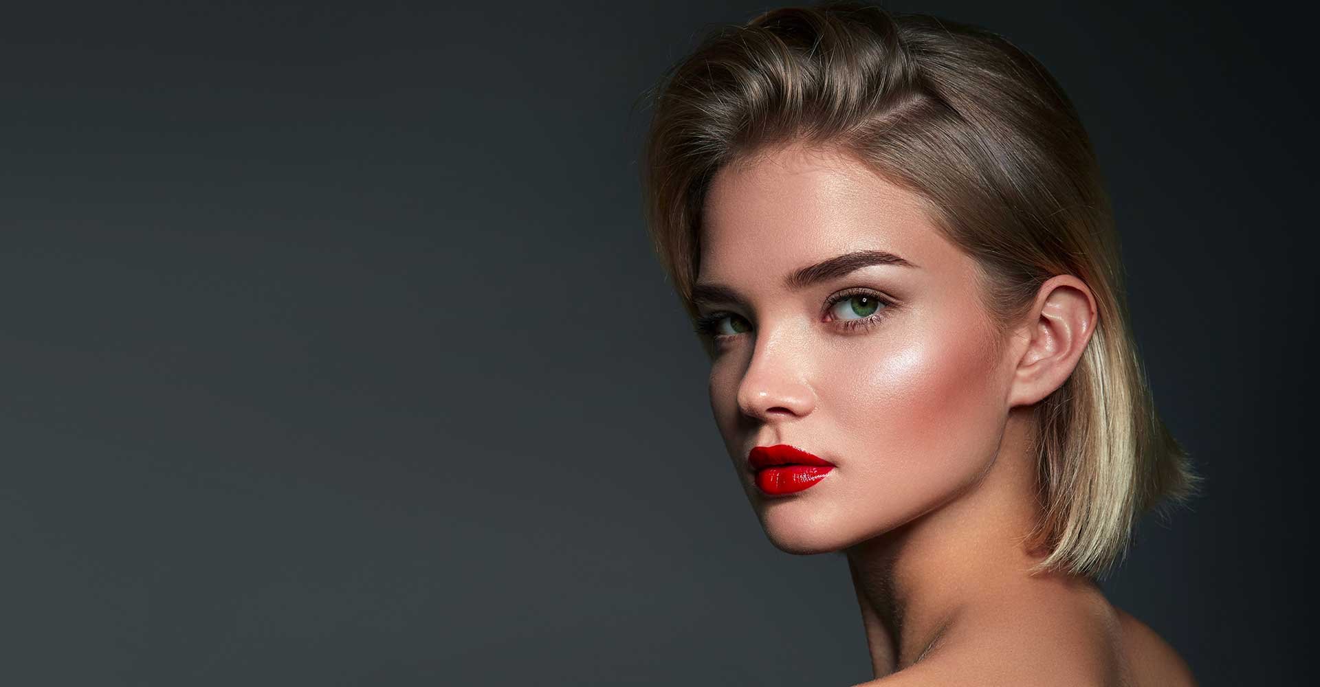 Modelo com cabelo pro lado esquerdo loiro e batom vermelho