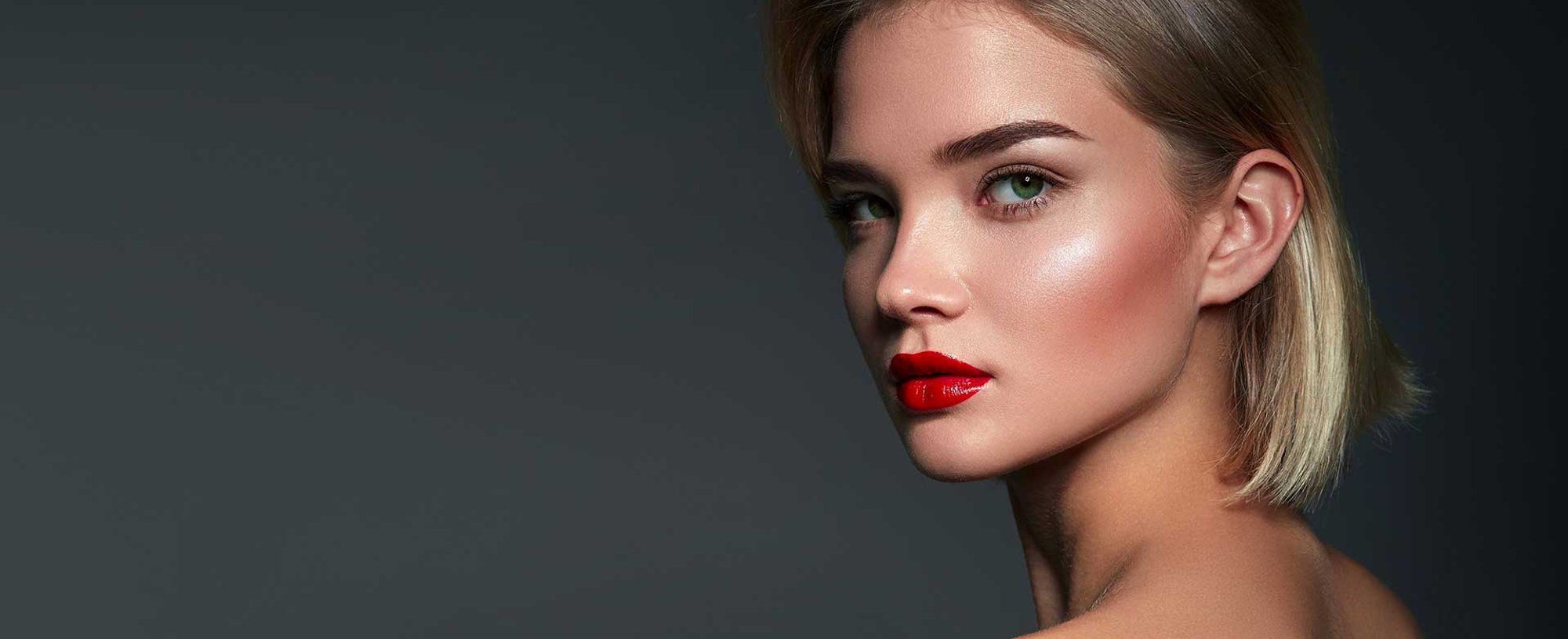 Modelo com cabelo pro lado esquerdo loiro e batom vermelho