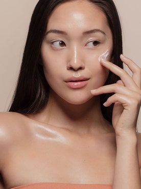 Modelo Asiatica Passando Produto Com Textura De Creme Cor Branca No Rosto