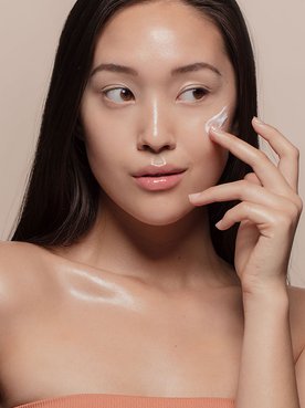 Modelo Asiatica Passando Produto Com Textura De Creme Cor Branca No Rosto