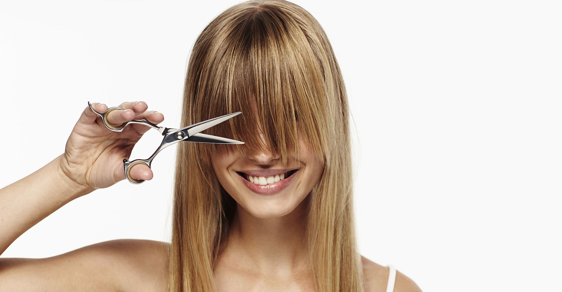 Mulher com uma tesoura cortando sua franja loira