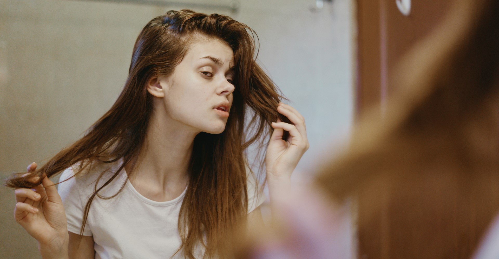 Modelo branca olhando seu cabelo danificado