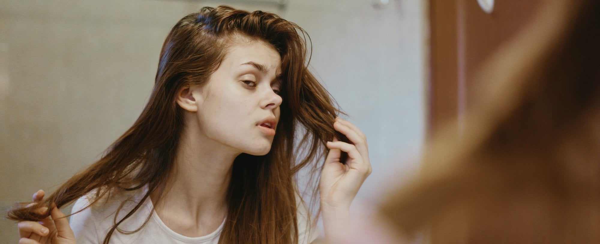 Modelo branca olhando seu cabelo danificado