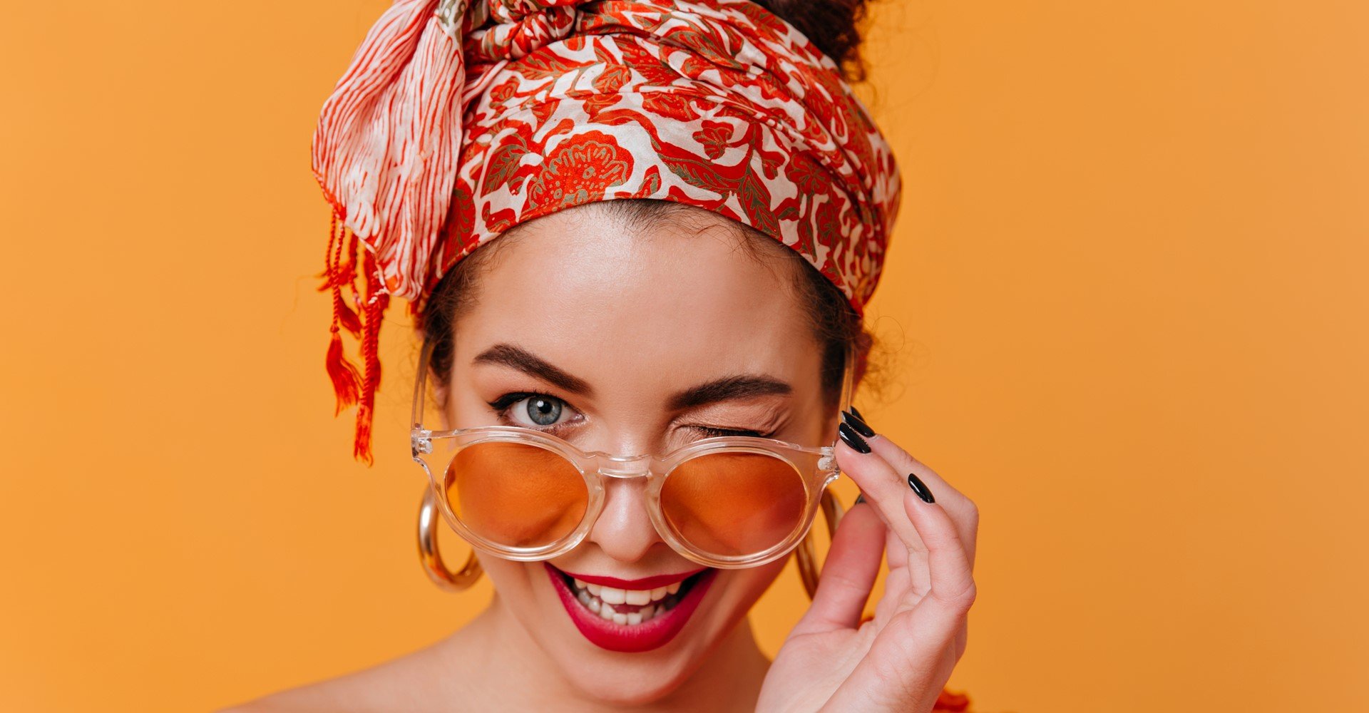 Modelo branca com batom vermelho, óculos de sol e tiara na cabeça