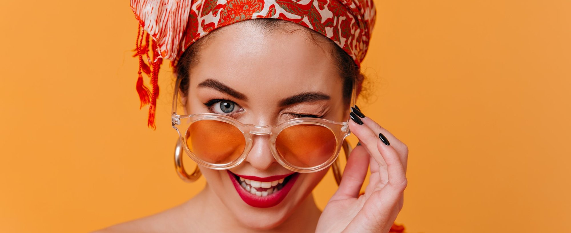 Modelo branca com batom vermelho, óculos de sol e tiara na cabeça