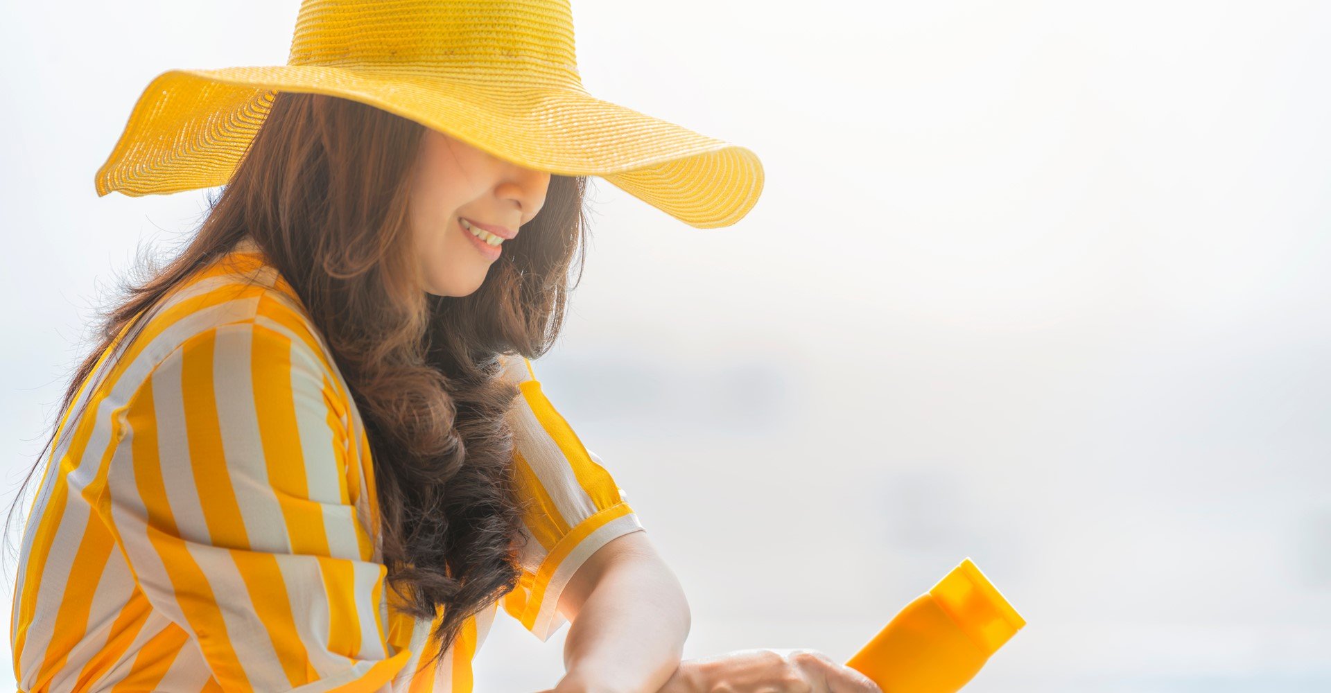 Modelo branca com chapéu e camisa amarela com listras