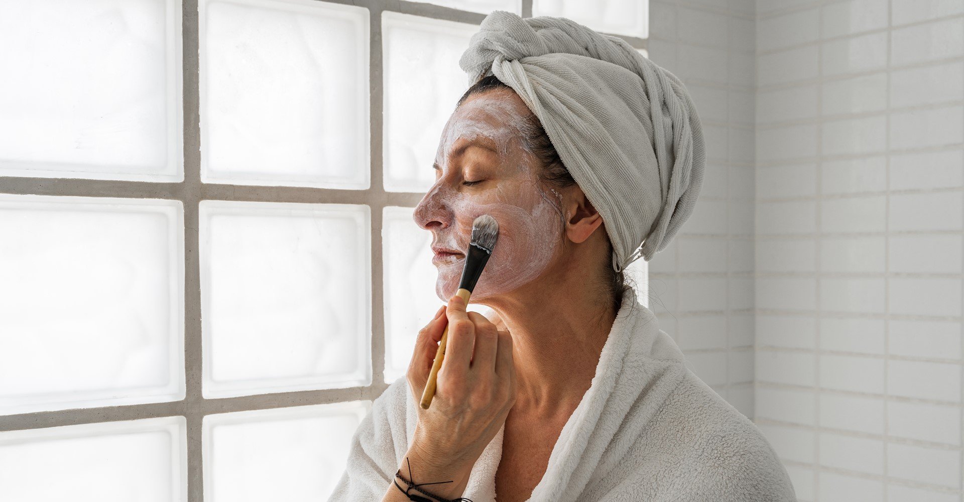 Modelo passando creme branco no rosto