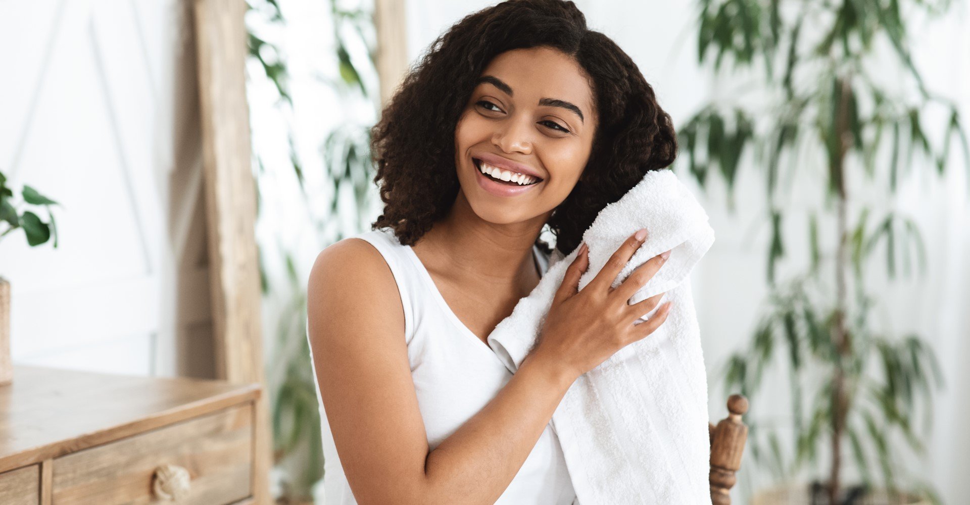 Modelo negra sorrindo secando seus cabelos