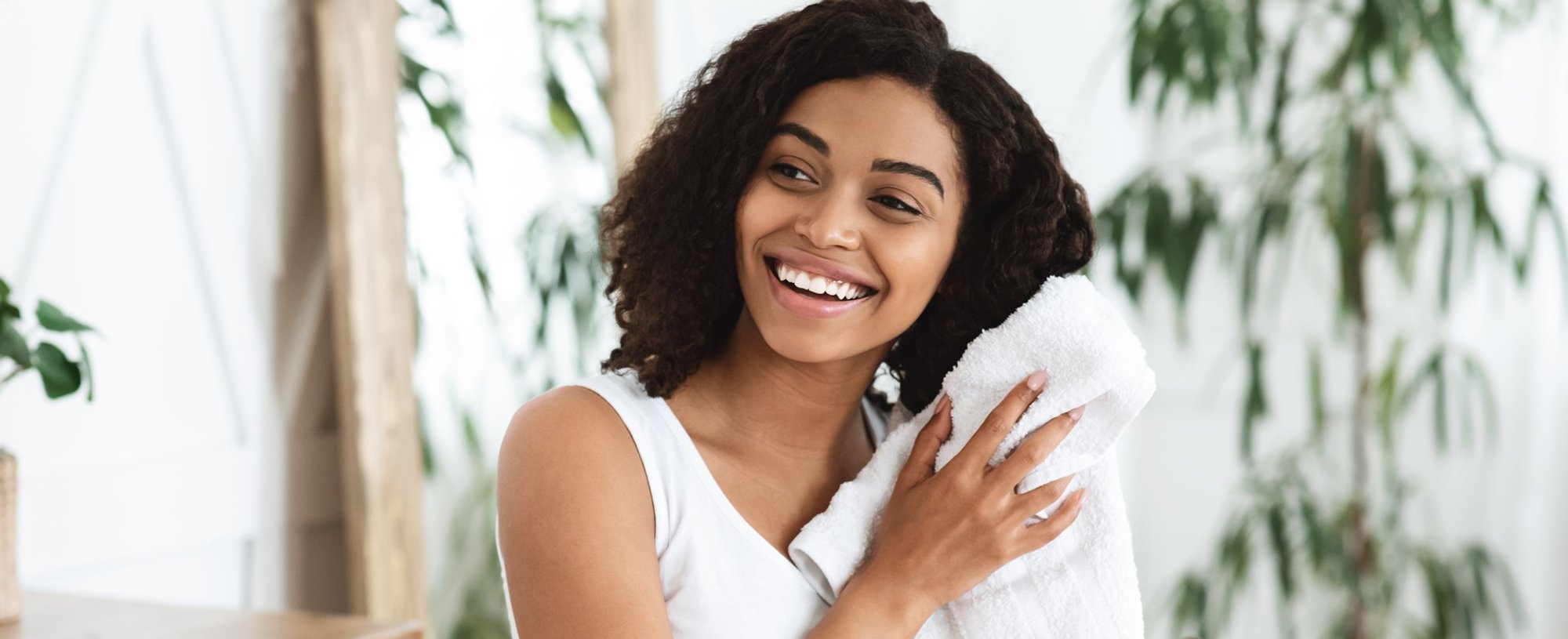 Modelo negra sorrindo secando seus cabelos