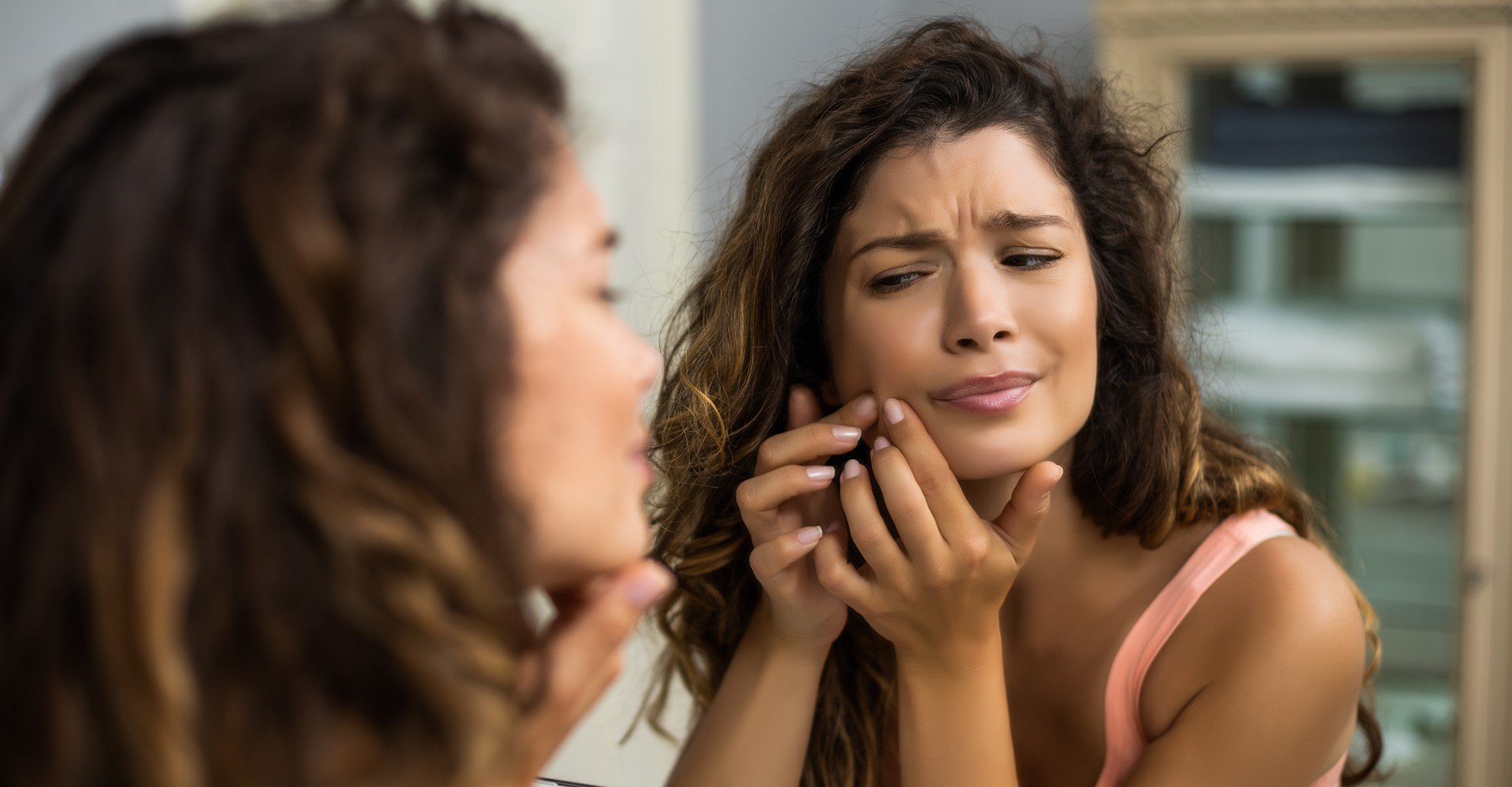Modelo negra se olhando no espelho e apertando acne do rosto