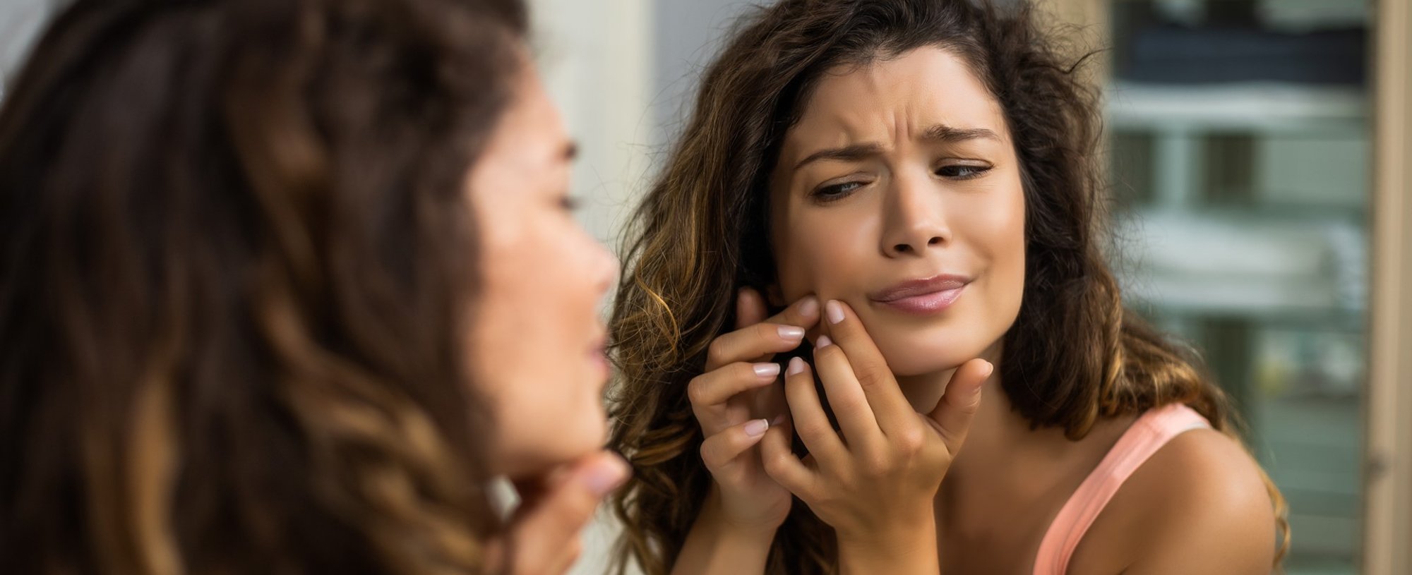 Modelo negra se olhando no espelho e apertando acne do rosto