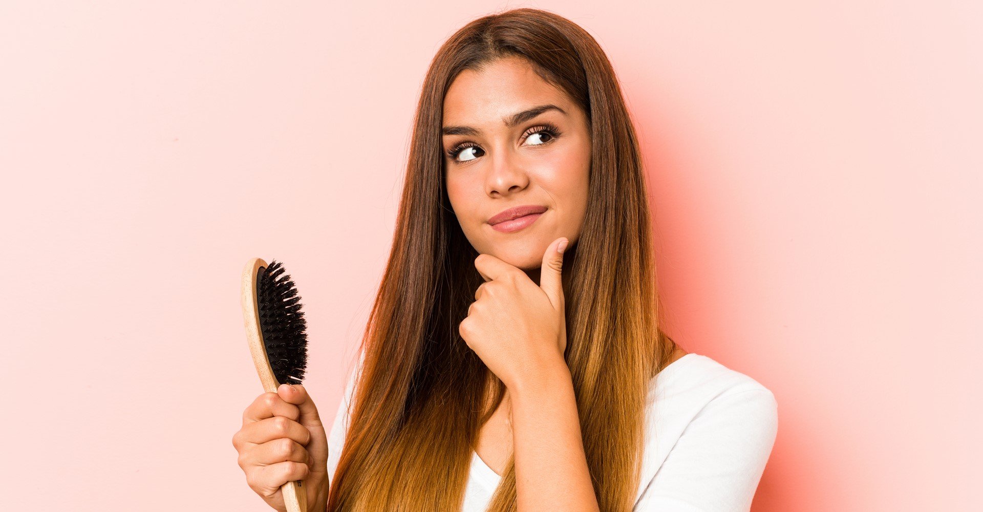 Modelo com cabelo liso e escova de pentear na mão