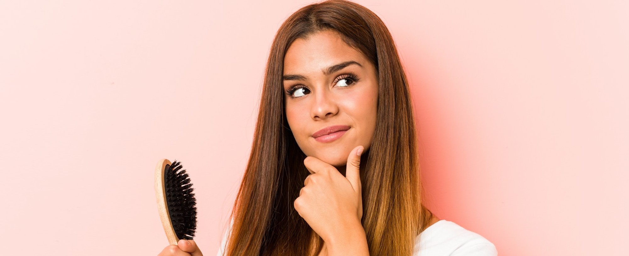 Modelo com cabelo liso e escova de pentear na mão