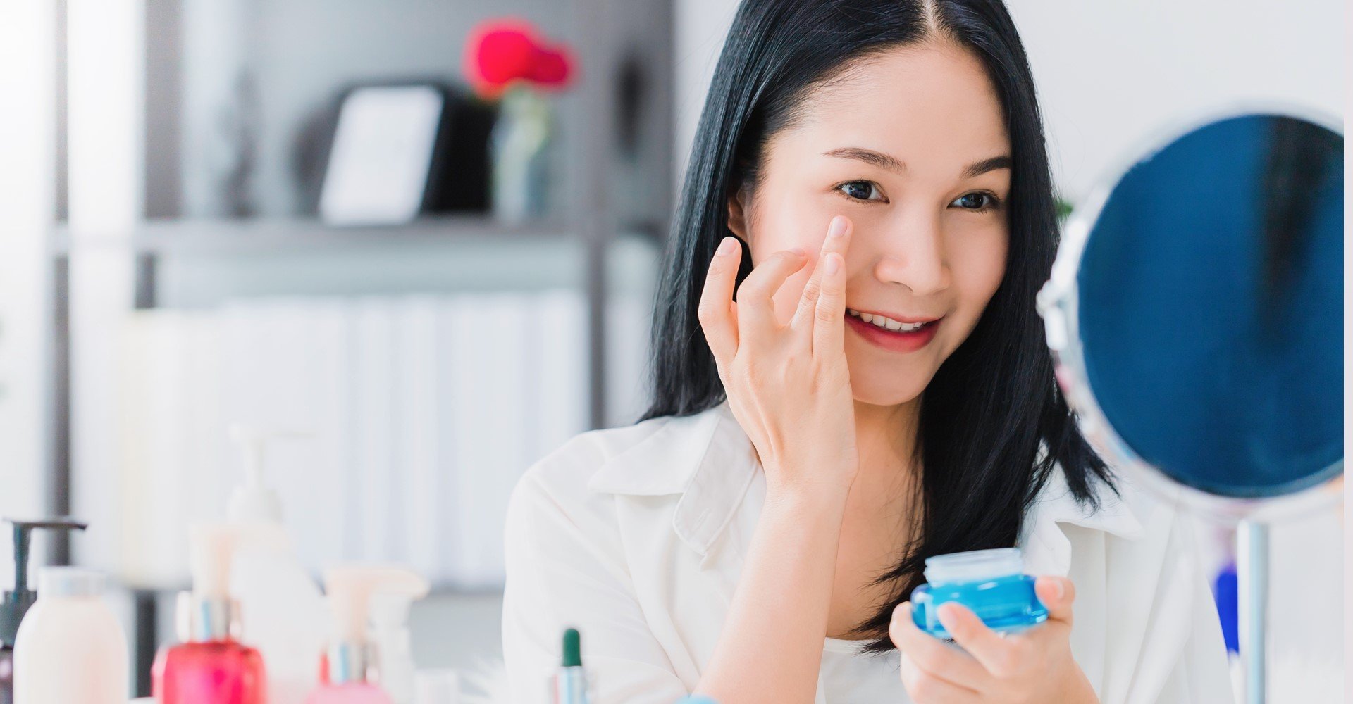 Modelo branca se olhando no espelho e passando creme