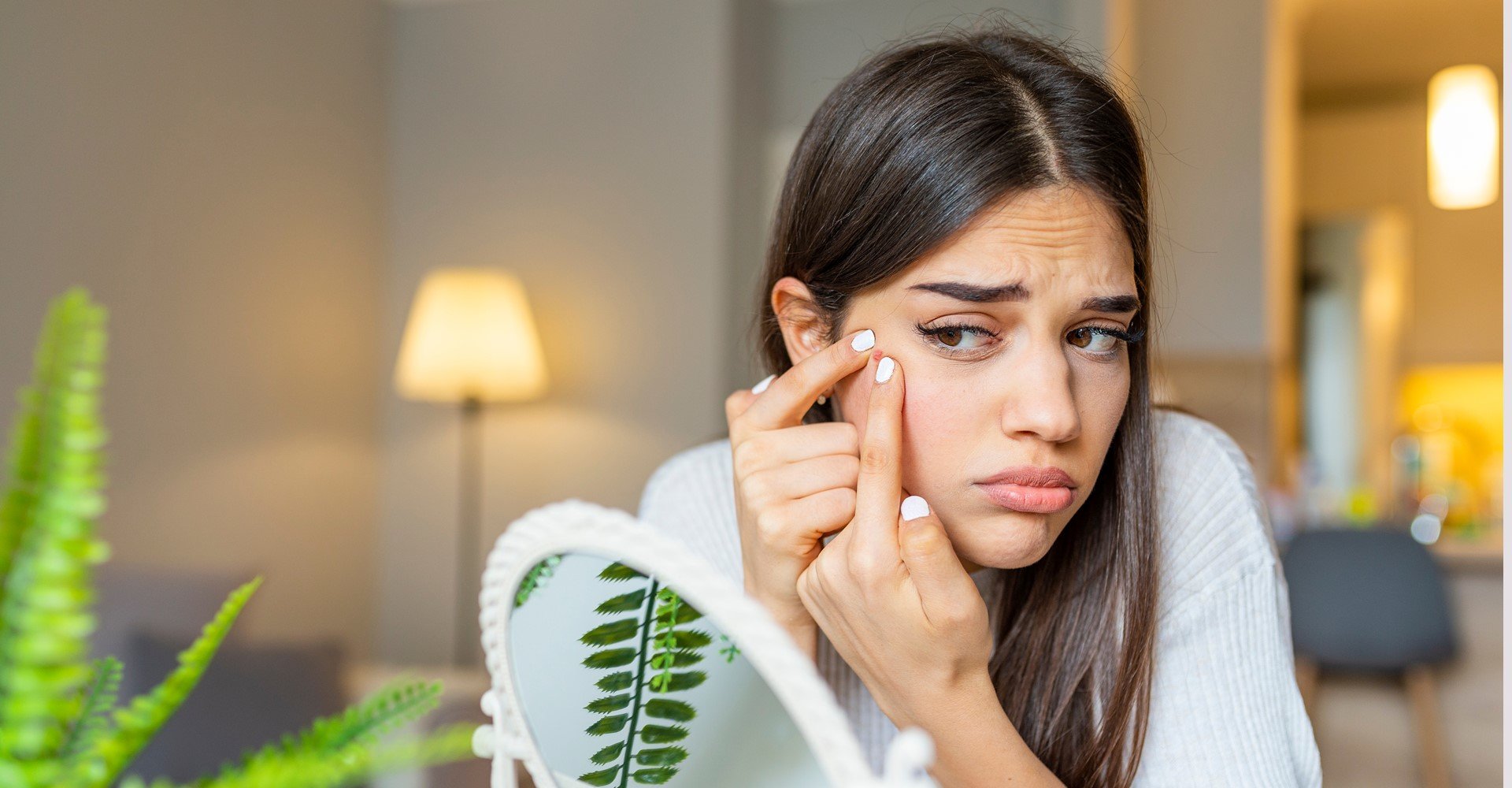 Modelo se olhando no espelho analisando acne