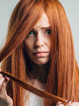 Modelo branca com cabelo ruivo e expressão de tristeza