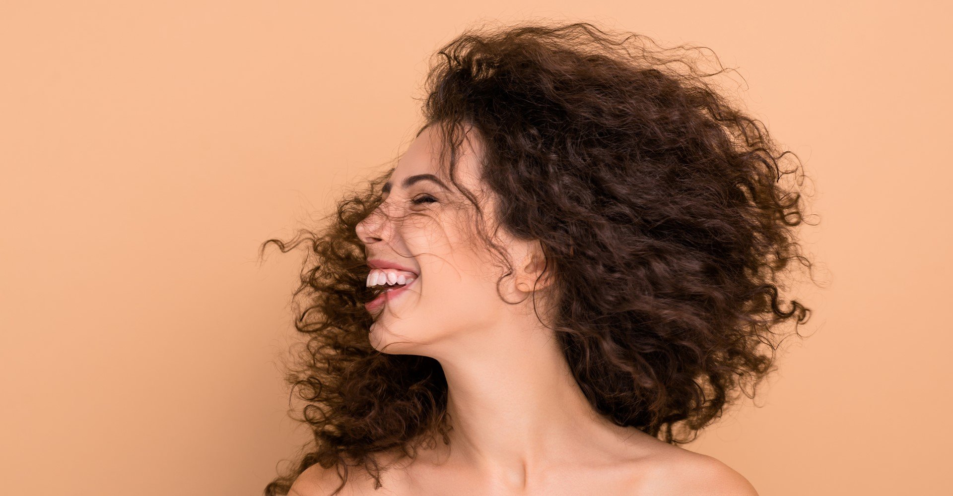 Modelo branca sorrindo com cabelo cacheado